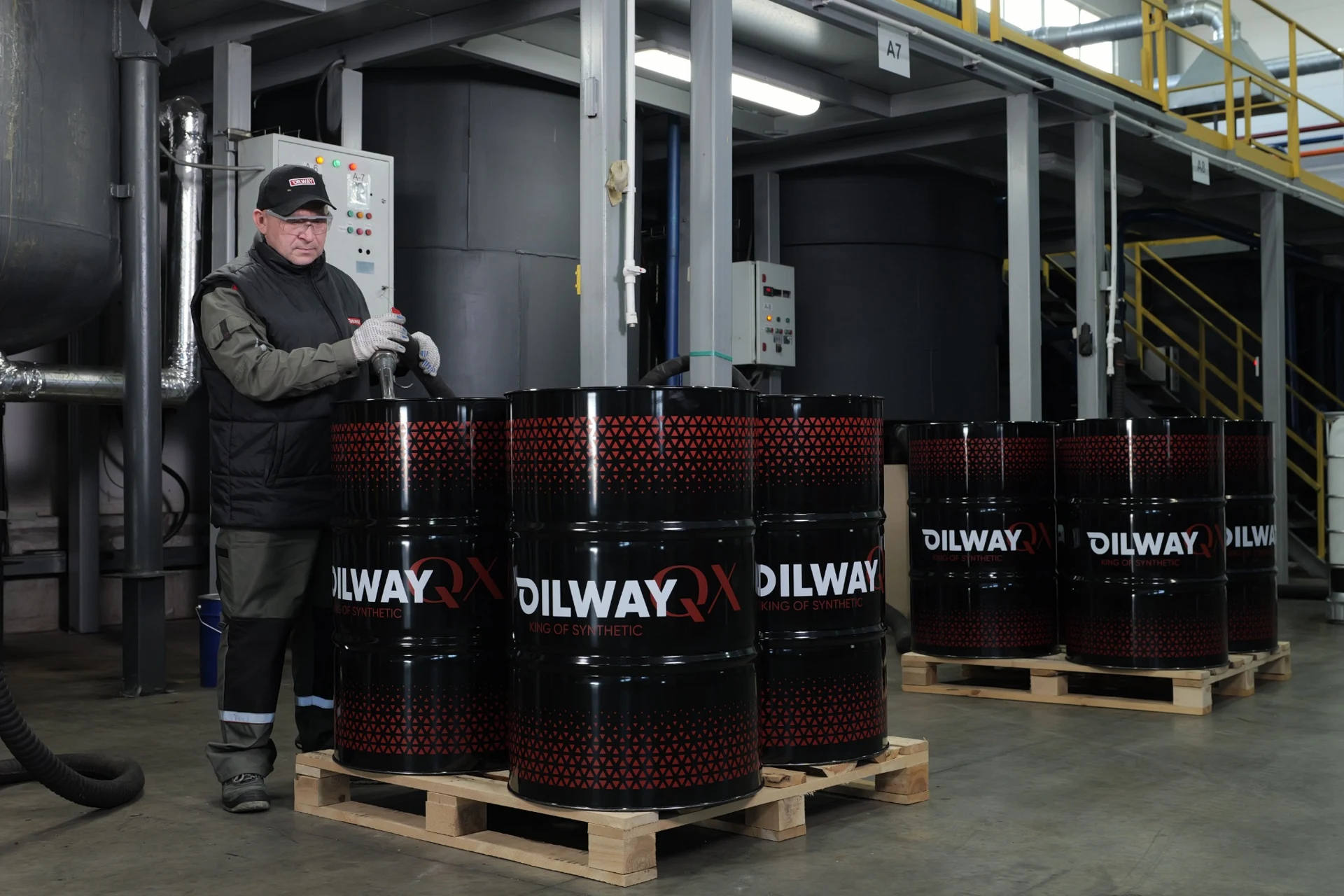 Сотрудник OILWAY у реакторов и бочек с готовой продукцией
